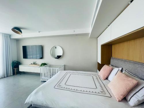una camera da letto con un grande letto bianco con cuscini rosa di Sweet Sea Side Eilat - סוויט סי סייד, אילת a Eilat