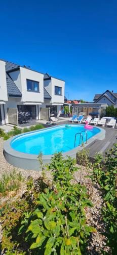 a swimming pool in front of a house at Domki-Apartamenty Polanki 2 - Sauna, Jacuzzi, Podgrzewany Basen in Łeba