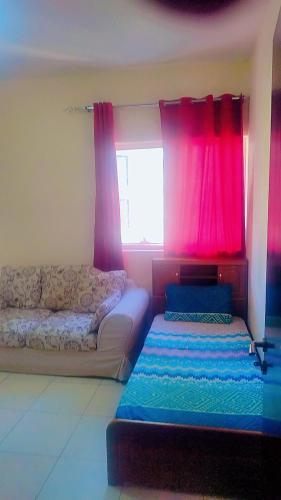 Cette chambre comprend deux lits et une fenêtre avec des rideaux roses. dans l'établissement Affordable Comfort: Cozy Room with Dedicated Bath & Twin Beds, à Charjah