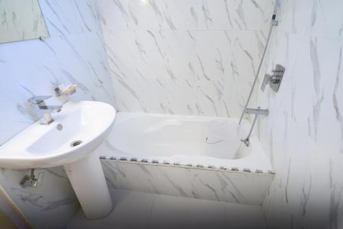 a white bathroom with a sink and a bath tub at Ganpati Hotel in Bhopal