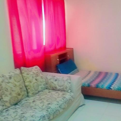 een kamer met een bank en een raam met roze gordijnen bij Affordable Comfort: Cozy Room with Dedicated Bath & Twin Beds in Sharjah