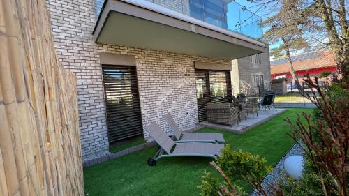 a patio with a bench and chairs on a lawn at Apartamenty Belni Hel Edyta i Maciej Wolak in Hel