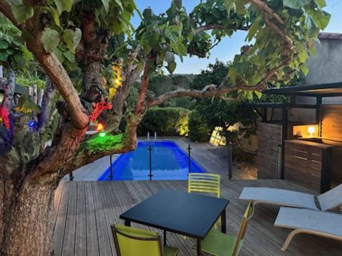 d'une terrasse avec une table, des chaises et un arbre. dans l'établissement Au calme, piscine et spa privés, à Roquebrune-sur Argens