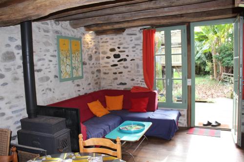 - un salon avec un canapé rouge et une cuisinière dans l'établissement le gîte du bain des oies, à Sauveterre