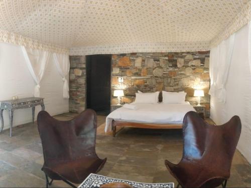 a bedroom with a bed and two chairs at The chocolate frog in Udaipur