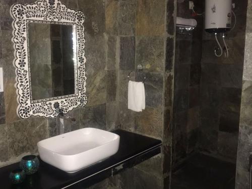 La salle de bains est pourvue d'un lavabo et d'un miroir sur un comptoir. dans l'établissement The Chocolate Frog, à Udaipur
