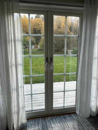 uma porta de vidro deslizante aberta com vista para um quintal em White little house on the countryside, close to Stockholm em Vidja