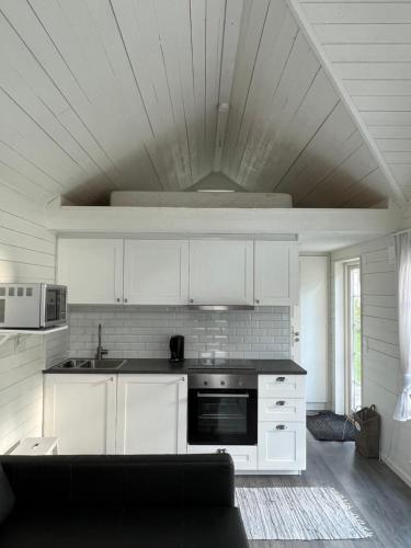 uma cozinha com armários brancos e um forno com placa de fogão em White little house on the countryside, close to Stockholm em Vidja