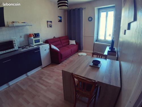 un salon avec un canapé rouge et une cuisine dans l'établissement Appartement Les Cozettes, à La Bourboule
