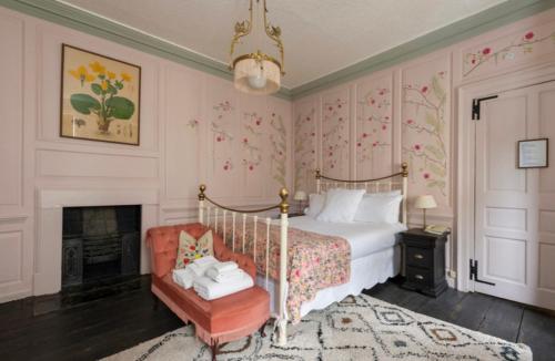 a bedroom with a bed and a chair and a fireplace at Bowlish House in Shepton Mallet