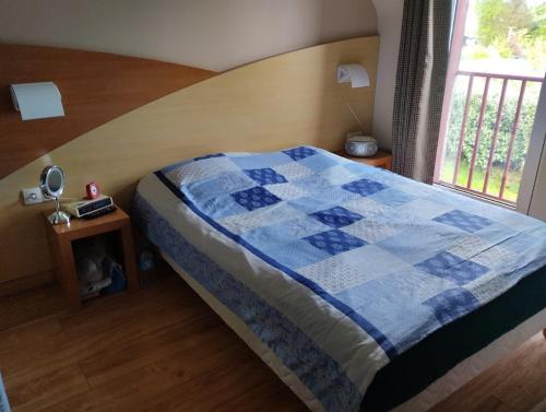 a bedroom with a bed with a blue quilt on it at Maison Tournebride in Meillac