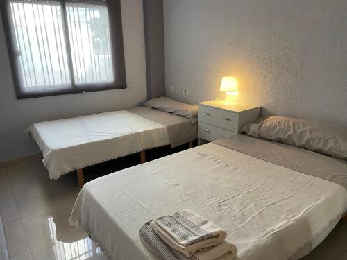 Pokój z dwoma łóżkami i lampką na stole w obiekcie APARTAMENTO CERCANO AL CENTRO w Walencji
