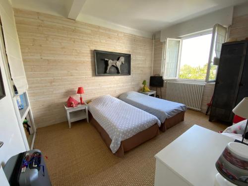 1 dormitorio con 2 camas y ventana en RÉF 344 - LARMOR-PLAGE Appartement centre bourg avec balcon plages et commodités à pied, en Larmor-Plage