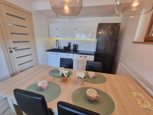a kitchen with a wooden table with chairs and a dining room at Apartament z kominkiem nad Jeziorem Czorsztyńskim in Frydman