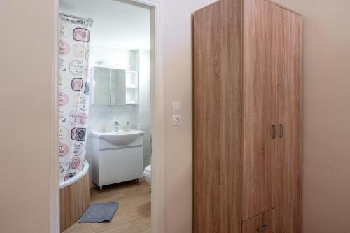 a bathroom with a wooden cabinet next to a sink at Γκαρσονιέρα 2 δίπλα στη θάλασσα! in Antikyra