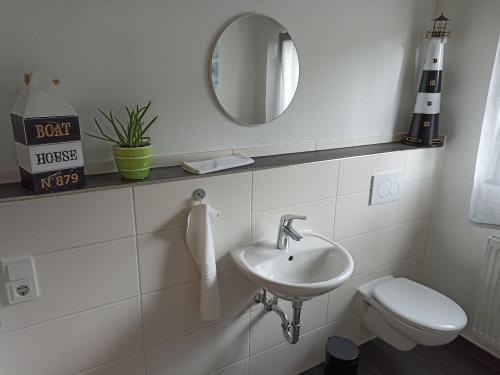 ein Badezimmer mit einem Waschbecken, einem WC und einem Spiegel in der Unterkunft Ferienwohnung Erftalblick in Hardheim