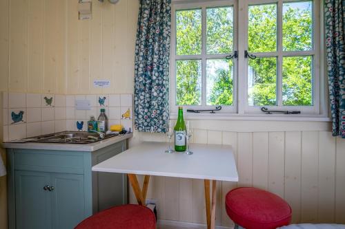 ウスターにあるThe Shepherd's Hut at Beechcroftのキッチン(白いテーブル、赤い椅子2脚付)