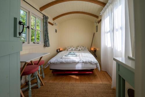ウスターにあるThe Shepherd's Hut at Beechcroftのベッドとテーブルと窓のある寝室