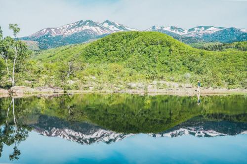 a mountain reflection in a lake with mountains in the background at Raicho Onsen Inn in Matsumoto