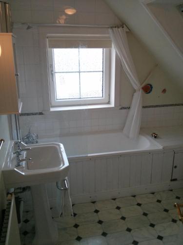 a bathroom with a sink and a tub and a window at Airebroc House in Uig