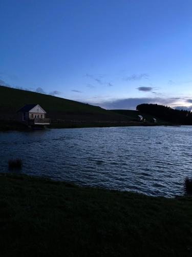 een groot meer met een huis in de verte bij East Learmouth Lakeside Lodges in Cornhill-on-tweed