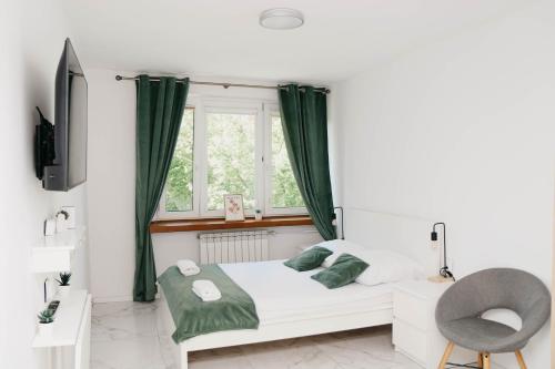 a bedroom with a bed with a window and a chair at Saska Kępa Luxe Apartment in Warsaw