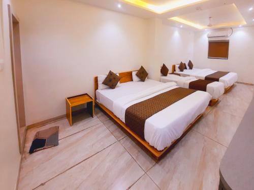 拉杰果德Hotel Nova Pride的白色墙壁的客房内的三张床