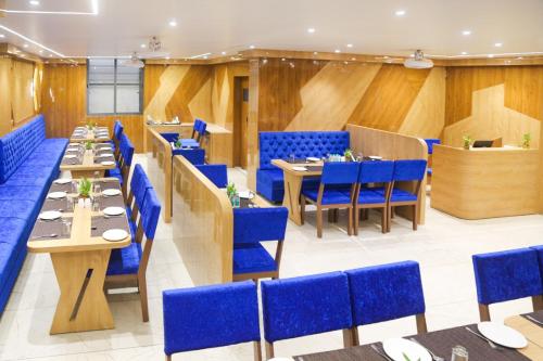 un restaurante con sillas y mesas azules en una habitación en Hotel Nova Pride, en Rajkot
