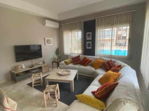 ein Wohnzimmer mit einem Sofa und einem TV in der Unterkunft APPARTEMENT BORDURE PLAGE in Kenitra