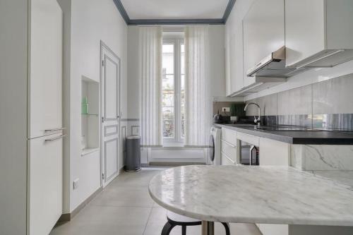 une grande cuisine blanche avec une table. dans l'établissement Pretty apartment close to Montmartre, à Paris