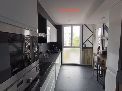 une cuisine avec des appareils en noir et blanc et une fenêtre dans l'établissement Location appartement refait à neuf, à Perpignan