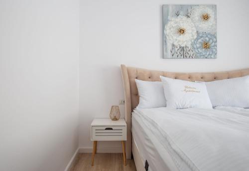 a bedroom with a bed with white sheets and a nightstand at Apartament Victoria in Satu Mare