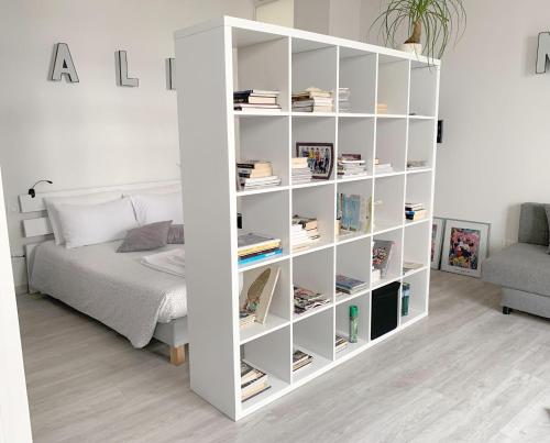 ein weißes Bücherregal neben einem Bett in einem Zimmer in der Unterkunft ALIMENTA open space city center in Lucca