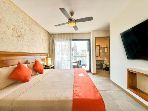 a bedroom with a bed and a flat screen tv at Grand Fifty Suites in Playa del Carmen
