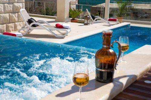 eine Flasche Wein und Gläser neben dem Pool in der Unterkunft Villa Arion in Mokošica