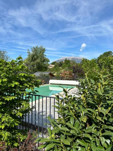 una piscina con una valla negra y árboles en Appartement 2 à 4 personnes, Une Pause au Vert en Châteauvieux