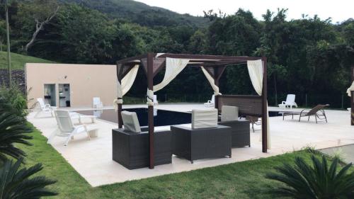 une terrasse avec un kiosque, une table et des chaises dans l'établissement Suíte no Mirante em Escarpas, à Capitólio