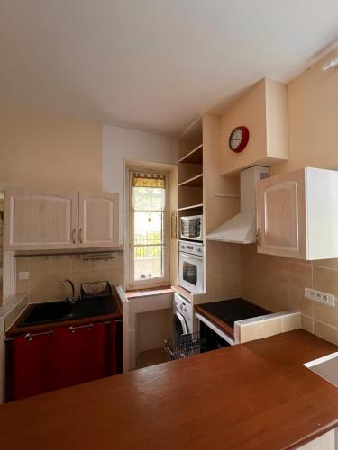 une cuisine avec des armoires blanches et une horloge rouge dans l'établissement Le Relais en Berry, à Montierchaume