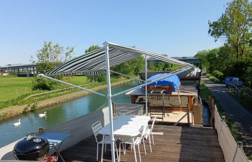 eine Terrasse mit Stühlen, ein Zelt und ein Boot in der Unterkunft Le logement du marinier in Eckwersheim