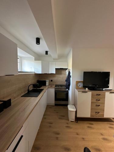uma cozinha com armários brancos e uma televisão de ecrã plano em Apartament u Majki em Bystra