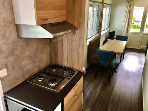 a kitchen with a stove and a table with chairs at Chalet Pallegarste 125 in Mariënberg