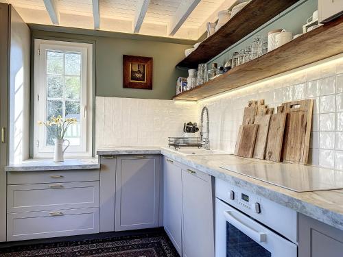 une cuisine avec des armoires blanches, un évier et une fenêtre dans l'établissement Villa Celsa YourHostHelper, à Bonneville-sur-Touques