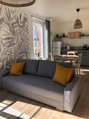 - un salon avec un canapé bleu et 2 oreillers jaunes dans l'établissement Appartement de la plage, à Barneville-Carteret