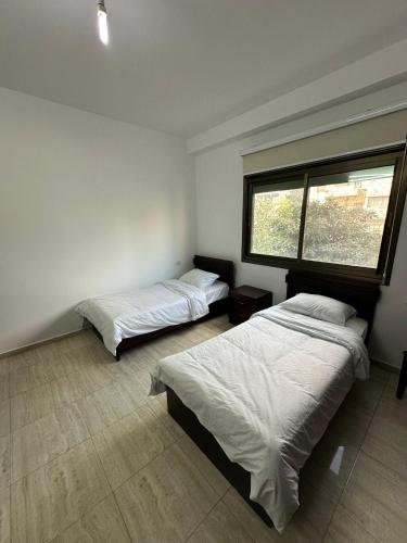 two beds in a room with a window at New Apartment in Nablus City in Mashabbe Sade