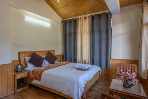 a bedroom with a bed and a table with flowers at Goroomgo Urban Monk Stays, Manali in Manāli