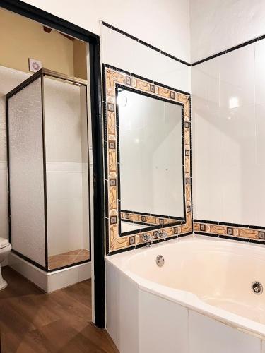 a bathroom with a bath tub and a mirror at Sie Casa Hotel in Villa de Leyva