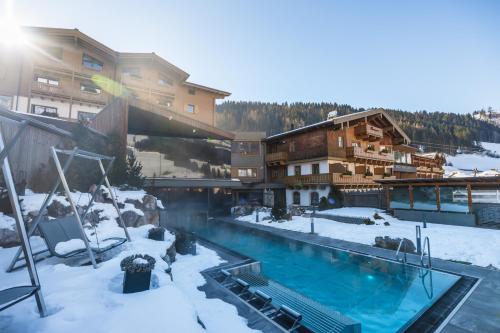 a resort with a swimming pool in the snow at Hotel Riederalm in Leogang