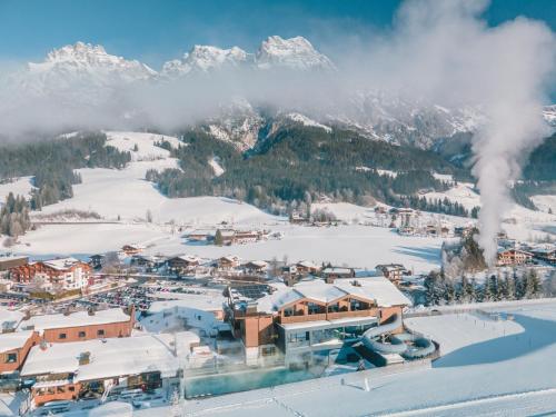 a town in the snow with mountains in the background at Hotel Riederalm in Leogang