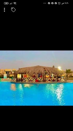 zwei Bilder eines Resorts mit Strohdach über einem Pool in der Unterkunft شالية ارضى فندقى قرية مينا 4الياحل الشمالى in Alexandria