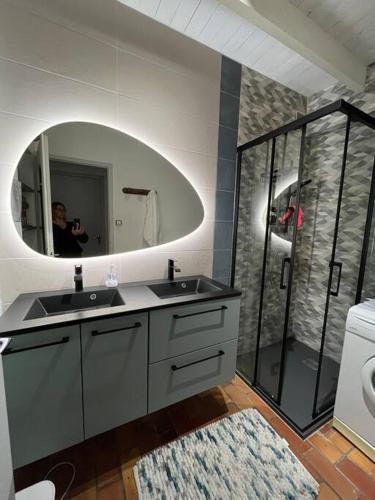 un homme prenant une photo d'une salle de bains avec un miroir dans l'établissement Maison de pêcheur au pied de la plage avec vélos, à Jard-sur-Mer